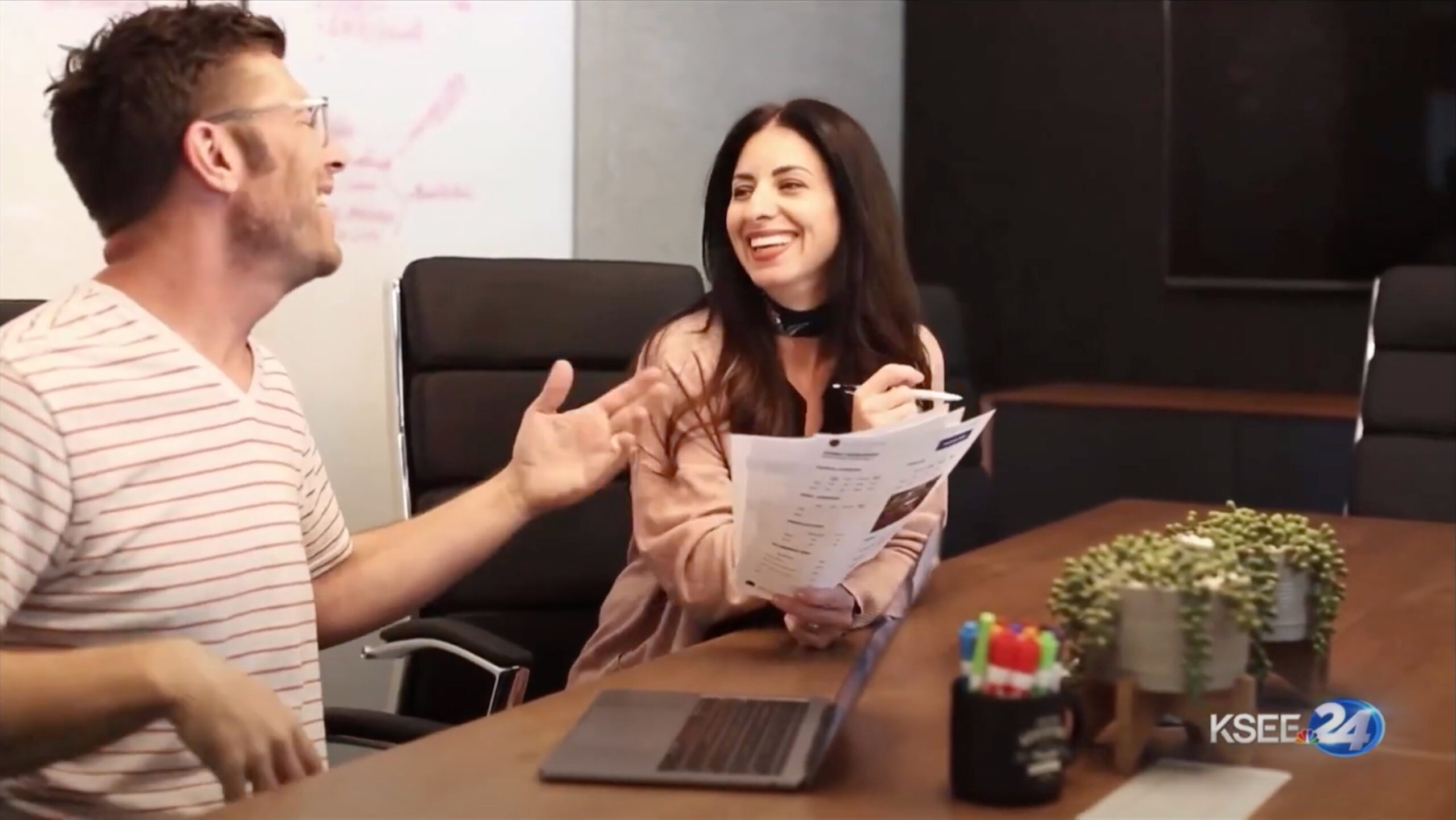 Photo of Archer & Hound co-owner Jessica Blanchfield holding paper reports and talking about a project with co-owner Aaron Coyne