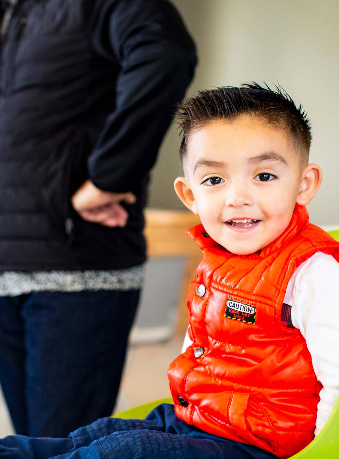 Archer-and-Hound-Advertising-First-5-Fresno-Child-Friendly-Business-Awards Small boy with dark hair and a deep orange vest, sitting and smiling at the camera